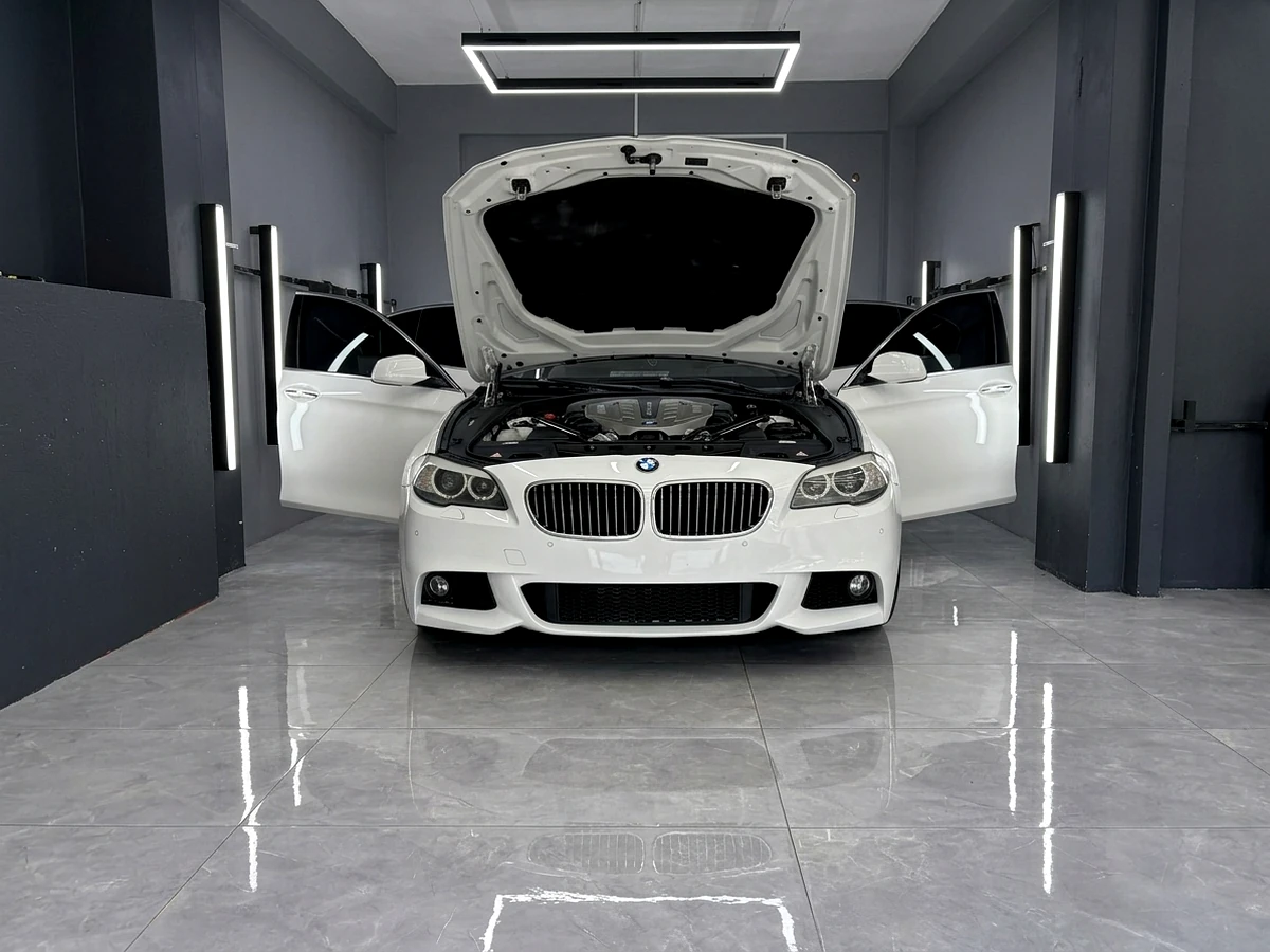 Beyaz BMW 5 Serisi stüdyoda kapılar açık detaylı yüzey ve seramik hazırlığı — Sezer Garage 54